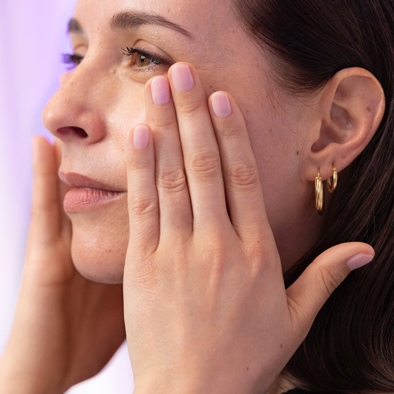 Woman applying wrinkle reducing cream to her face with both hands
